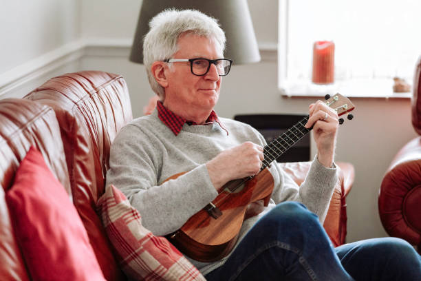 istock Happy senior man playing ukulele at home 1470593410