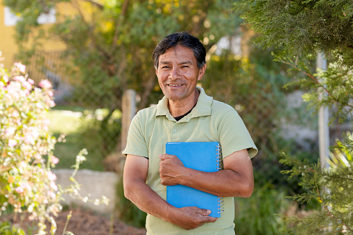 Hispanic father holding notebooks in rural area - latin teacher - mayan man learning