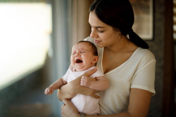Mother taking car of a crying newborn baby stock photo
