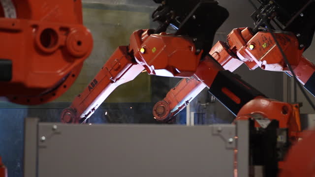 Robots welding metal parts in an industrial factory assembly line