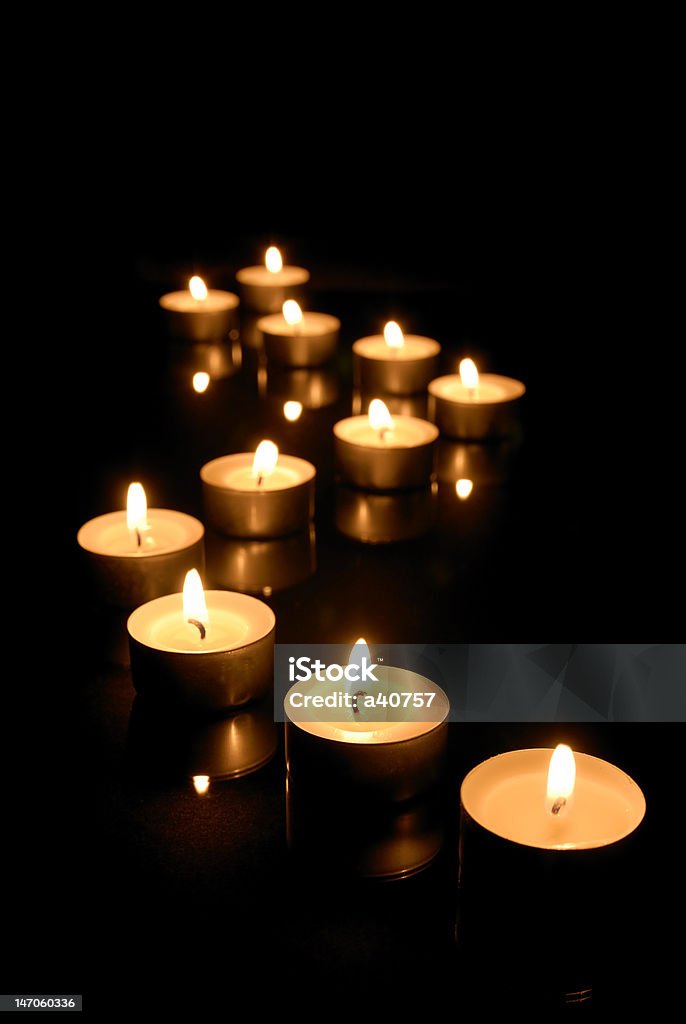 Burning candles Burning tea lights on black background. Black Color Stock Photo