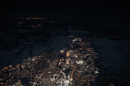 Aerial view of Reno, Nevada and Donner Pass at night in winter. The mountains are snow covered and Sacramento is in the distance.