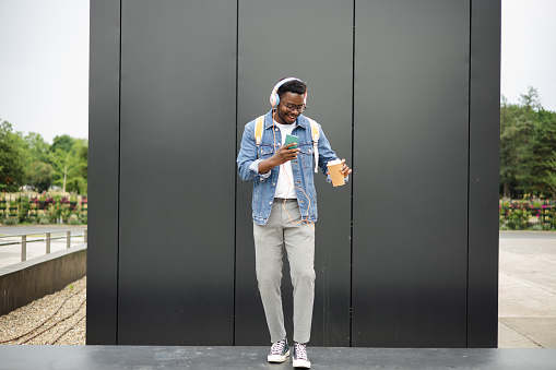Portrait of a young African American man listening to music and enjoying coffee outdoors