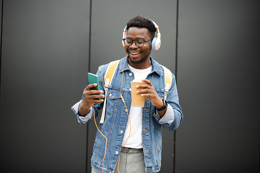 Portrait of a young African American man listening to music and enjoying coffee outdoors
