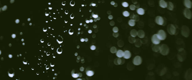 istock Atmospheric minimal monochrome backdrop with rain droplets on glass. Wet window with rainy drops and dirt spots closeup. Blurry minimalist background of dirty window glass with raindrops close up. 1470608743