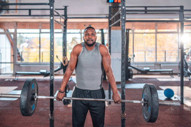 Bearded male athlete practicing deadlift with barbell at health club. Man is exercising with weights. He is training at gym.