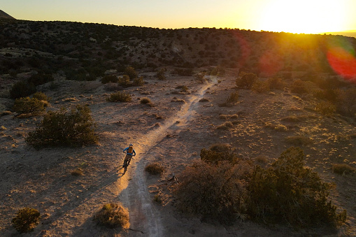 man riding his mountain bike through the high desert singletrack.  airborne drone photography.
