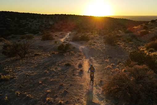 man riding his mountain bike through the high desert singletrack.  airborne drone photography.