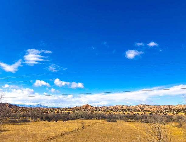 Española, NM: Golden winter fields and distant hills under a vibrant blue sky. Espanola is in northern New Mexico, about 25 miles north of Santa Fe.