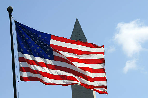 istock sun lit flag in front of Washington monument 147062120