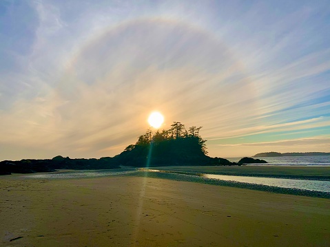 Sun halo at the beach just before the sun dips behind a tiny treed island.