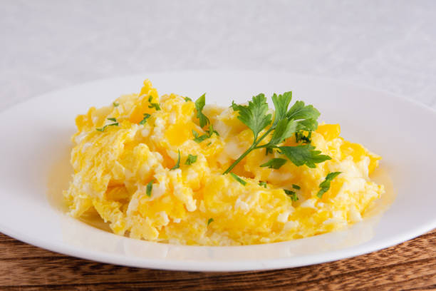 istock Scrambled eggs, omelette. Breakfast with pan-fried eggs. Texture of omelet on white plate on green mint linen textile tablecloth. Keto ketogenic diet. Soft light 1470622352