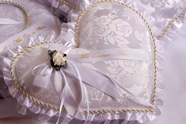 Quinceanera Pillow White, heart shaped quinceañera pillow with white flower, satin bowe and gold trim. quinceanera stock pictures, royalty-free photos & images