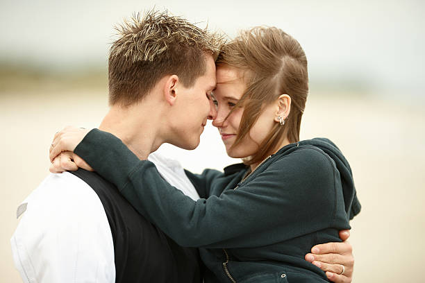 istock two young people walking on the beach holding tight 147062893