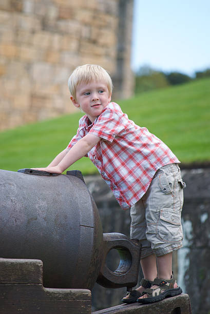 niño jugando en cannon, desde northumberland en castillo de alnwick - cannon alnwick castle alnwick castle fotografías e imágenes de stock