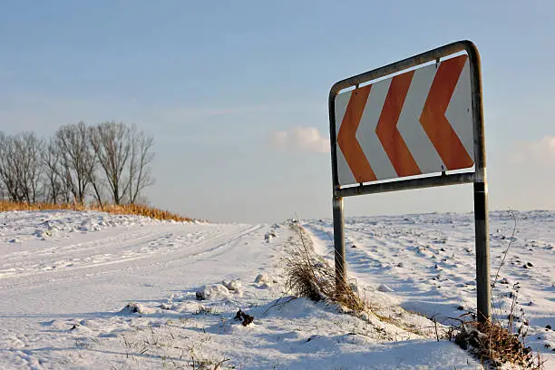 Lonely sign at snowcovered countryroad.Focus on Roadsign.