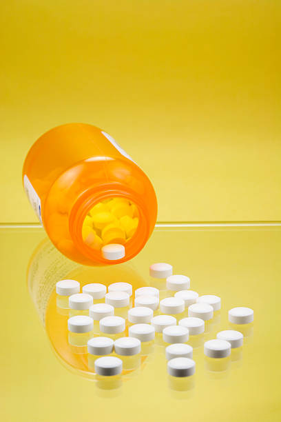 Tablets spilling from a bottle on glass shelf stock photo