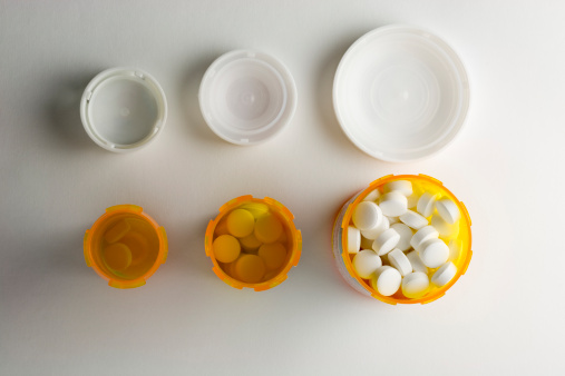 A row of three prescription medicine bottles increasing in size.