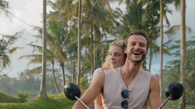 happy couple riding motorcycle on tropical island exploring beautiful travel destination together on motorbike ride at sunrise