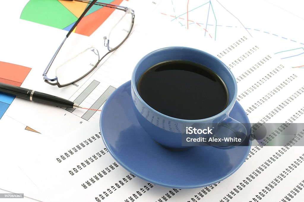 Tazza di caffè e penna a sfera e occhiali su accumulo di grafici - Foto stock royalty-free di Affari