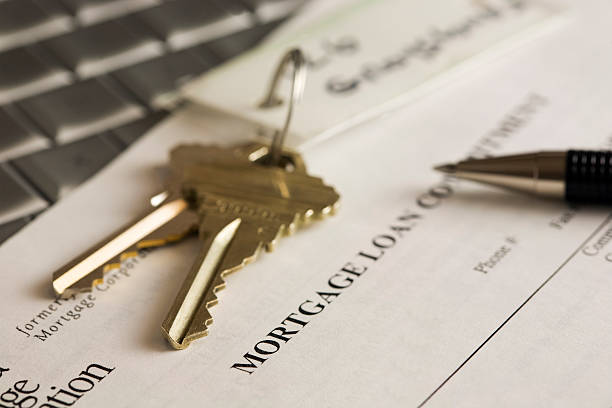 House keys, mortgage statement and pen sitting on a laptop stock photo