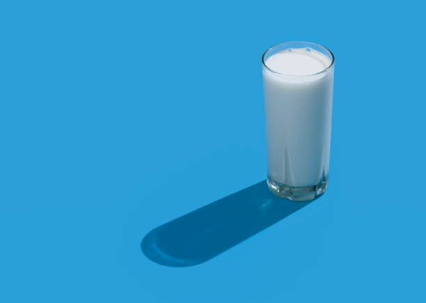 istock Glass of fresh milk with hard shadows on a blue background. 1470654496