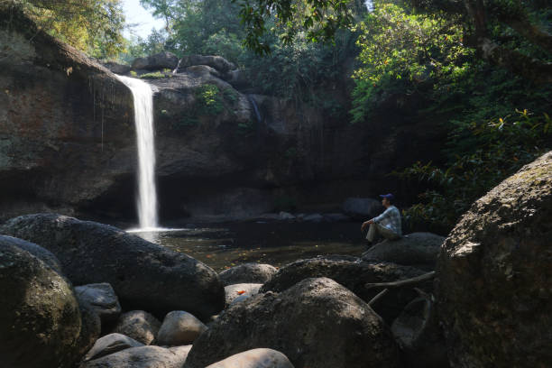 istock asian men sitting on the rock with water fall background. 1470654890