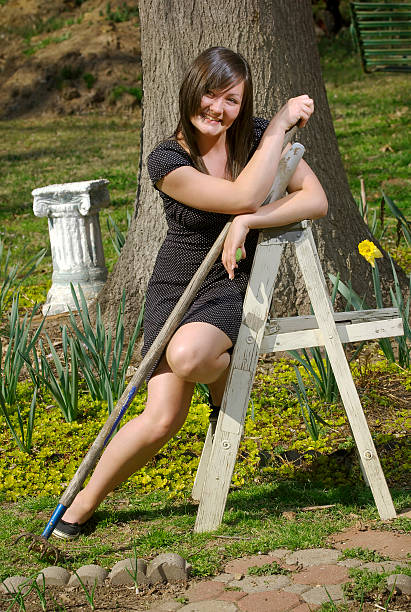 Teen girl with garden tools smiles stock photo