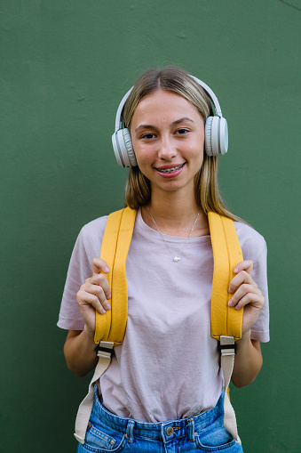 portrait of female student with headphones on green background
