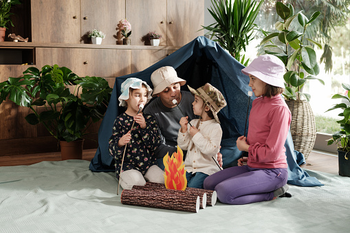 Family as father with three children playing camping game at home, concept for activities for activities at home for children