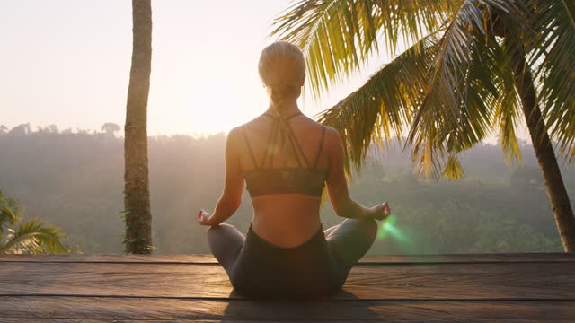 yoga woman meditating at sunrise practicing mindfulness meditation exercise sitting on deck outdoors in nature 4k