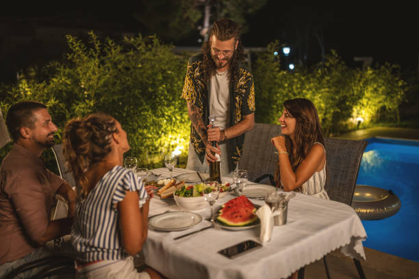 istock Young man opening wine bottle at summer dinner 1470660773