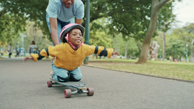 Child, skateboard and park fun of a girl with dad together on vacation riding on a sidewalk. African family, happiness and freedom of a kid with dad, parent love and support on pavement for skating