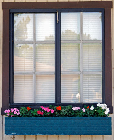 A window box on the side wall of a small depot building displays multi-colored impatiens flowers.
