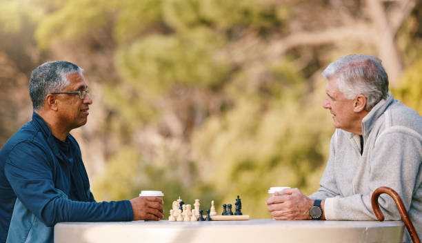 istock Chess, nature and retirement with senior friends playing a boardgame while bonding outdoor during summer. Park, strategy and game with a mature man and friend thinking about the mental challenge 1470663788