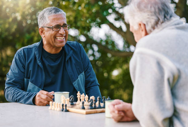 ajedrez, naturaleza y retiro con amigos mayores jugando un juego de mesa mientras se unen al aire libre durante el verano. parque, estrategia y juego con un hombre maduro y un amigo pensando en el desafío mental - juego de ajedrez fotografías e imágenes de stock