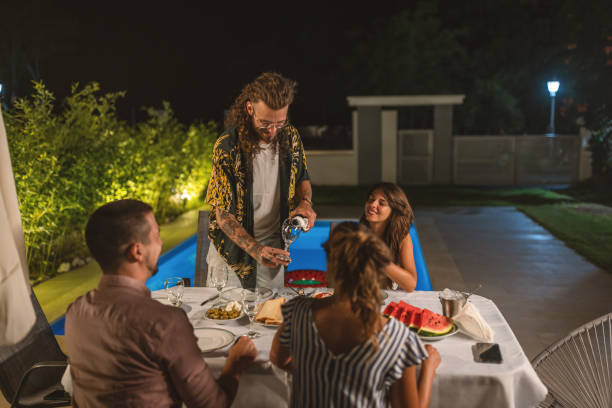 istock Young man serving wine at summer dinner party 1470664894