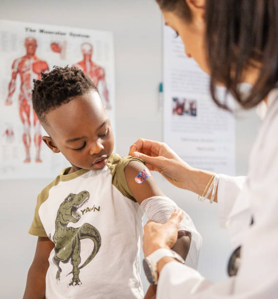 Doctor putting an adhesive bandage on a boy's arm during a visit