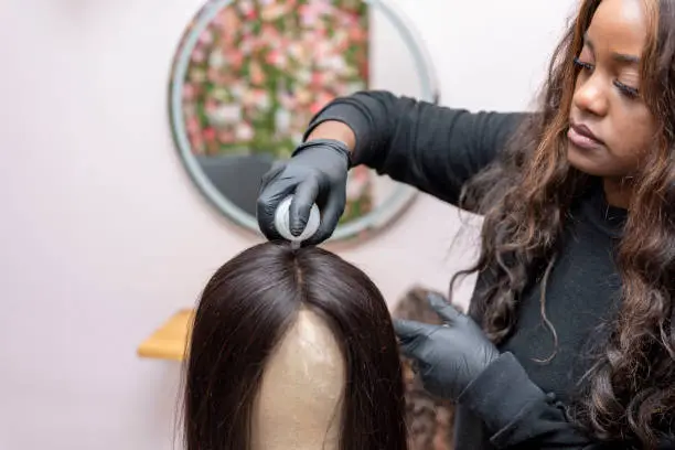 Photo of Woman training hairdressing with mannequin head putting the hair product