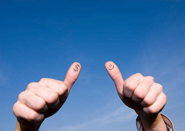 Smiley and a dollar painted on fingers over blue sky stock photo