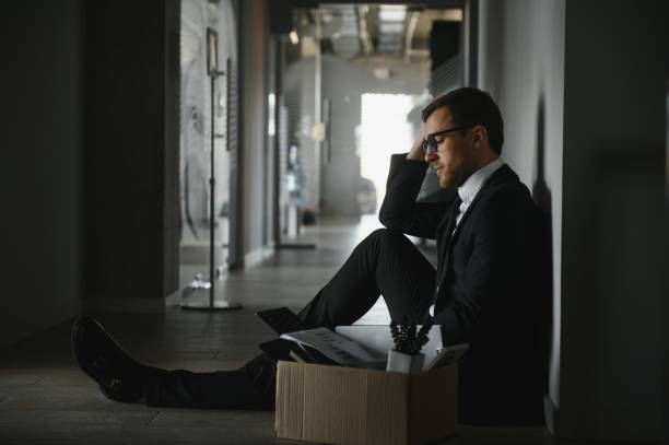 istock Sad Fired. Let Go Office Worker Packs His Belongings into Cardboard Box and Leaves Office. Workforce Reduction, Downsizing, Reorganization, Restructuring, Outsourcing. Mass Unemployment Market Crisis 1470669143