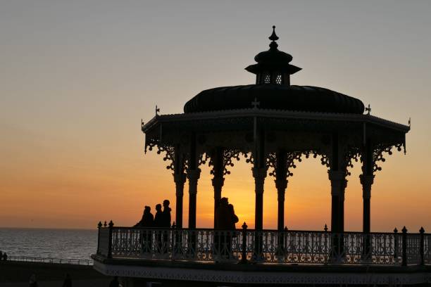 istock a pavilion with people walking past it by the ocean at sunset 1470669200