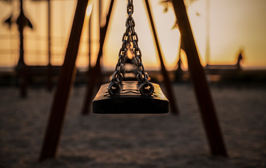 Closeup of swing on playground during sunset