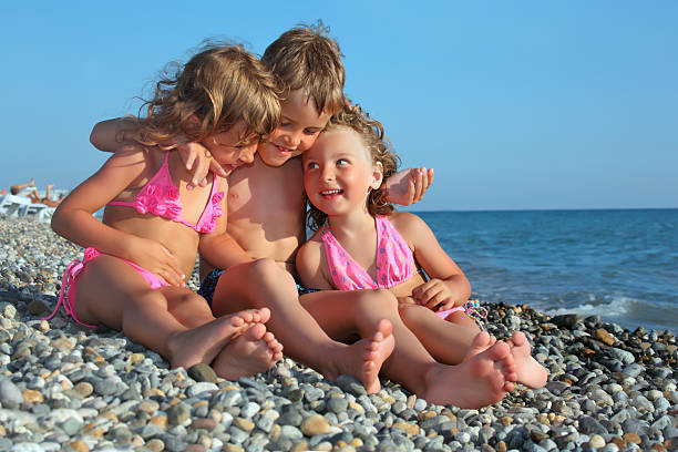 istock Children three together sitting on stony beach 147067030