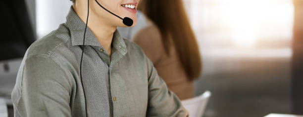 istock Young man with headsets is talking to a client, while sitting in modern sunny office. Call center operators at work 1470672709
