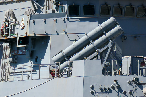 Four of eight of the canisters for launching Harpoon anti-ship missiles on the forward deck of HMAS Arunta, an Anzac Class frigate of the Royal Australian Navy.  She is docked at Garden Island, Sydney Harbour, in preparation for an open day to the public during Navy Week, the first open day since the Covid pandemic.  This image was taken on a sunny afternoon from Woolloomooloo Bay on 25 February 2023.