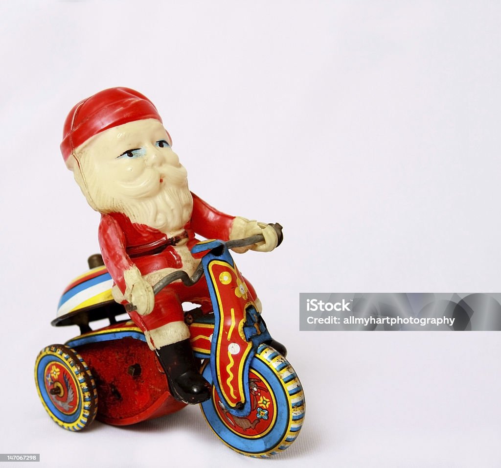 Vintage Santa Toy on Tin Motorcycle A tiny plastic Santa on a wind-up tin motorcycle or trike, rings a bell as he drives.  From the 1930's or 40's. Room for copy. Christmas Stock Photo