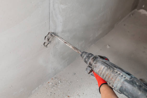 istock Master electrician lays a cable in a concrete wall and mounts an electrical outlet 1470673784