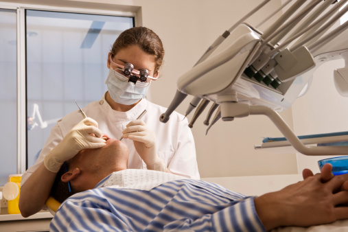 Female dentist examining male patient's teeth