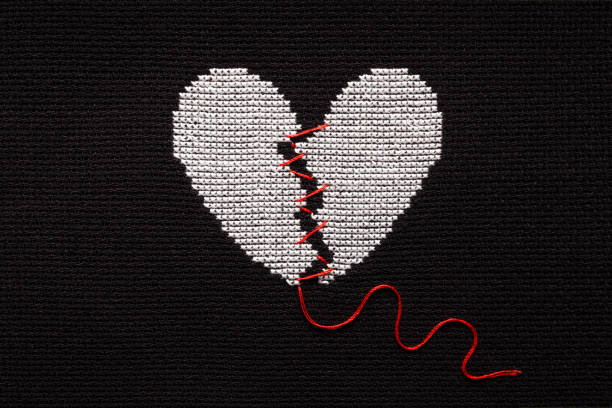 istock A broken heart is embroidered with white threads on black fabric. 1470674374